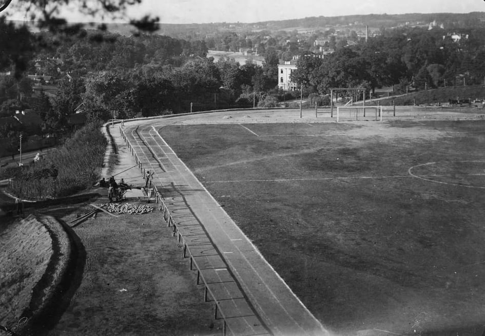 Nuotraukoje stadionas apie 1926 m. Namas, kuris matosi dešiniau – T. Kosciuškos g. 30. Pastato, kuriame dabar Šventojo Sosto nunciatūra, dar nėra. Jis atsiras vėliau – apie 1937 m.