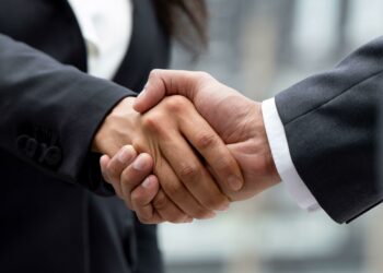 2H7C2D7 Businesswoman in formal attire making handshake with business partner outdoors in the city, panoramic banner proportion
