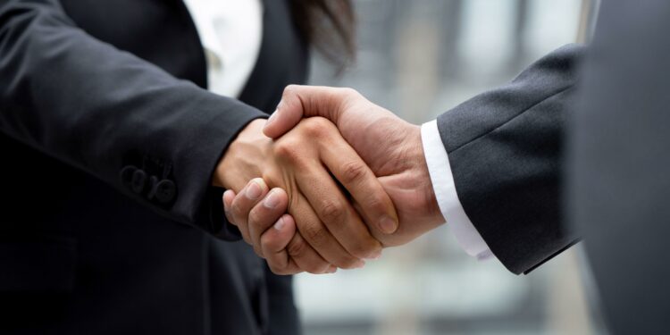 2H7C2D7 Businesswoman in formal attire making handshake with business partner outdoors in the city, panoramic banner proportion