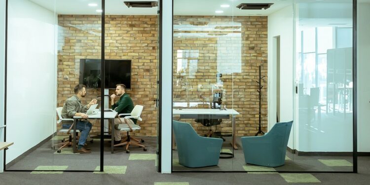 Два профессионала беседуют, удобно сидя в гостиной офиса в окружении зелени и элементов современного дизайна.
